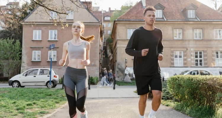 Two young adults jogging on a city path, showcasing an active lifestyle in an urban environment.